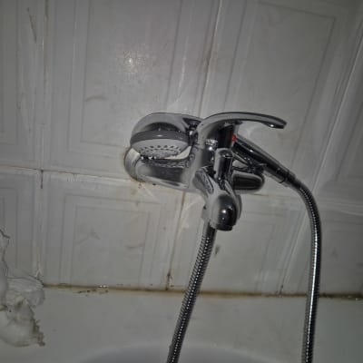 ברז מקלחת עם ראש מקלחת על קיר אריחים