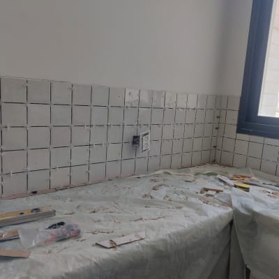 קיר עם אריחים מותקנים, כלי עבודה וחומרי בנייה