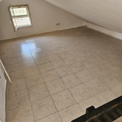 חדר עם רצפת אריחים נקייה ותקרה משופעת