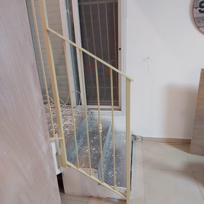 מעקה מתכת צהוב ליד דלת זכוכית עם מסגרת לבנה