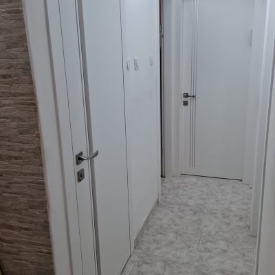 דלתות לבנות במסדרון עם רצפת קרמיקה