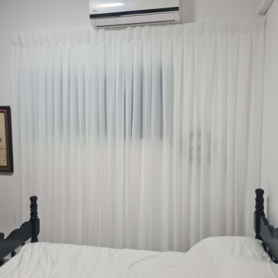 וילון לבן תלוי על חלון בחדר שינה עם מיטה ומזגן