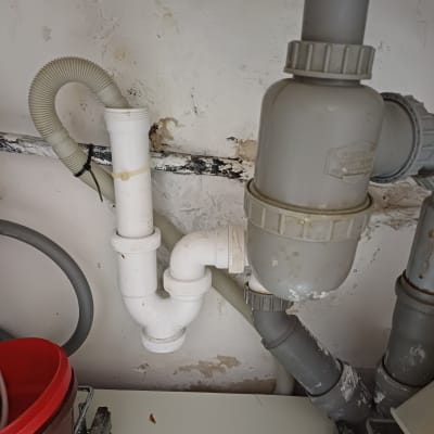 צינורות פלסטיק לבנים ואפורים מתחת לכיור