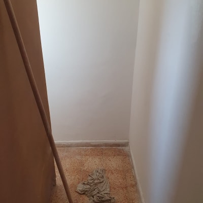 קיר צבוע בלבן עם מקל וצבע על הרצפה