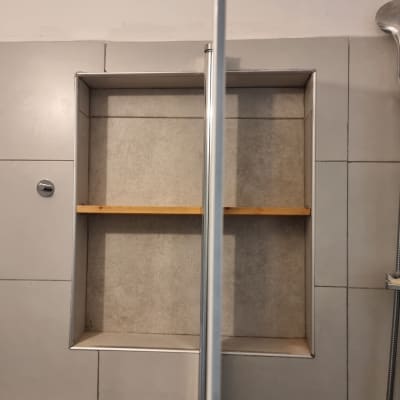 מדף עץ מותקן בתוך קיר אריחים בחדר אמבטיה