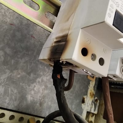 חוטים שרופים מחוברים למפסק חשמלי בארון חשמל