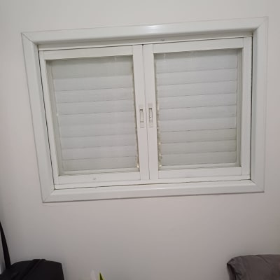 חלון זכוכית עם תריסים סגורים וחפצים על שולחן קטן