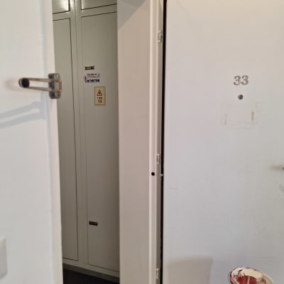 דלי צבע אדום עם מכסה לבן ליד דלת