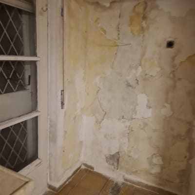 קיר עם קילופי צבע ותיקונים ליד חלון