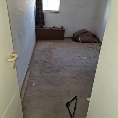 חדר ריק עם שטיח מלוכלך וקולב על הרצפה