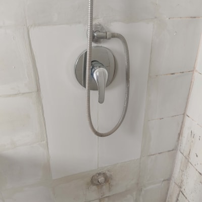 ברז מקלחת עם צינור גמיש על קיר אריחים