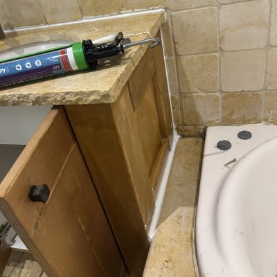 אקדח סיליקון ליד כיור וחיפוי קיר