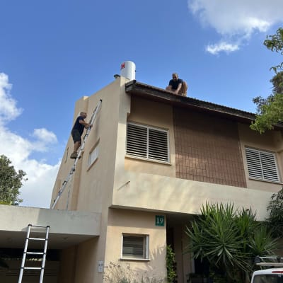 שני אנשים עובדים על דוד שמש על גג בית