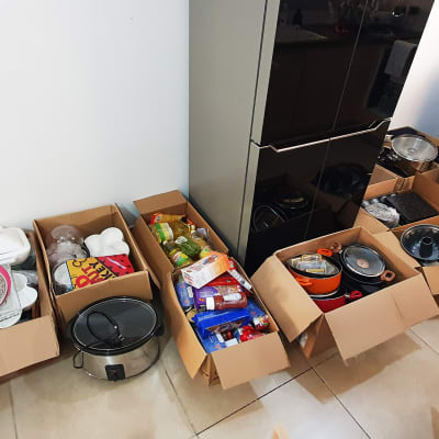 קופסאות קרטון עם כלי מטבח ומצרכים על הרצפה