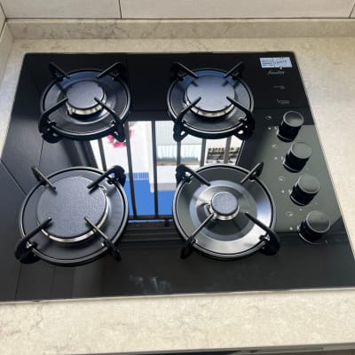 כיריים גז שחורות עם ארבעה מבערים וכפתורי שליטה