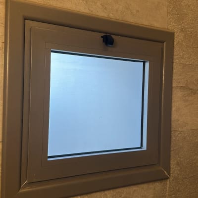 חלון זכוכית עם מסגרת מתכת על קיר אריחים