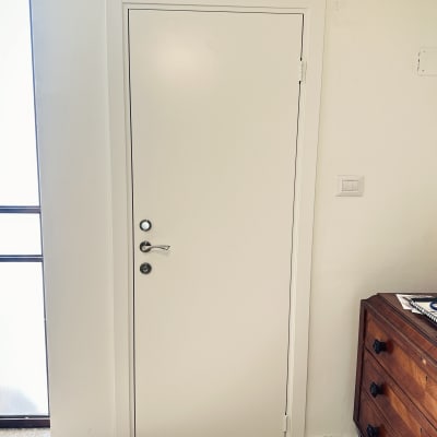 דלת לבנה מותקנת בקיר לבן עם ידית כסופה