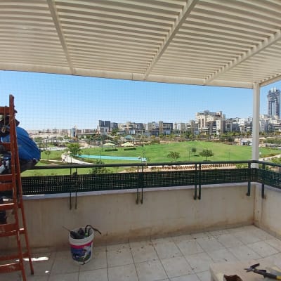 אדם על סולם מתקין רשת למניעת יונים