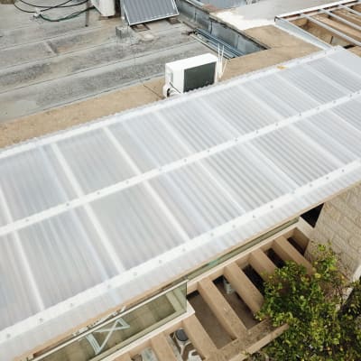 גג פלסטיק שקוף מותקן על מבנה עץ בגינה