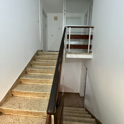 גרם מדרגות עם מעקה עץ וקירות לבנים