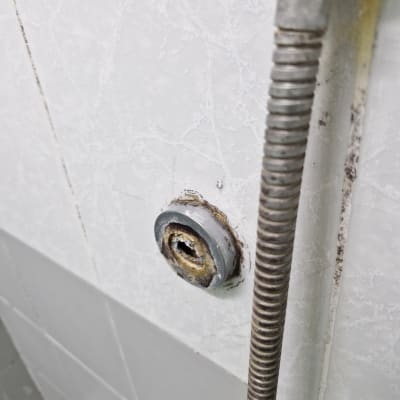 צינור מתכת חלוד בקיר אריחים לבן