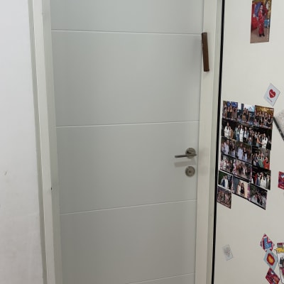 דלת לבנה עם ידית מתכת ותמונות על הקיר