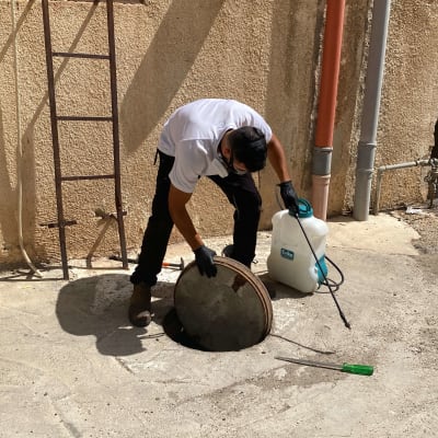אדם פותח מכסה ביוב עם ציוד הדברה