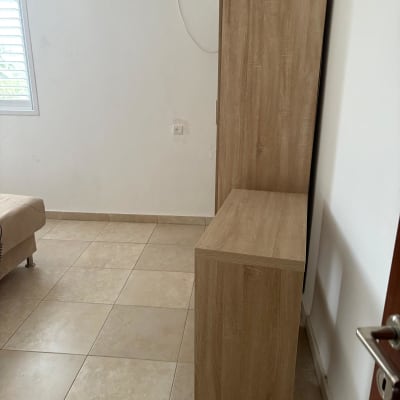 ארון עץ בחדר עם רצפת קרמיקה ומזגן על הקיר