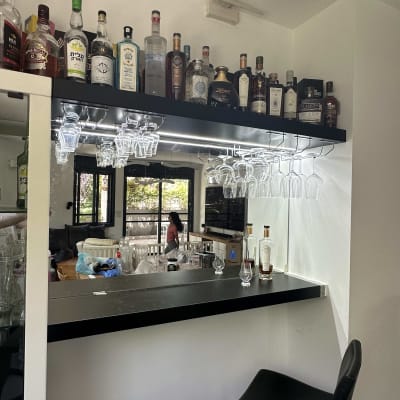 מדף עם בקבוקי אלכוהול וכוסות תלויים