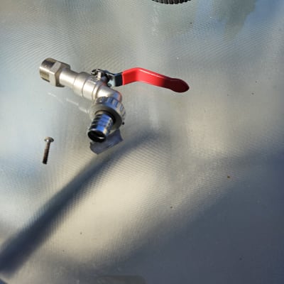 ברז מתכת עם ידית אדומה על שולחן זכוכית