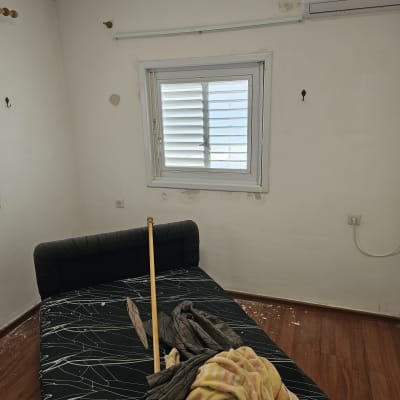 חדר עם מיטה, מזגן ומוט עץ, לא מציג עבודה בתחום