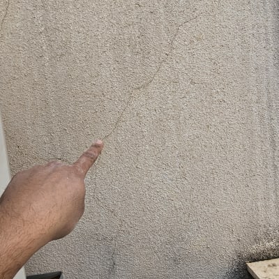 אצבע מצביעה על סדק בקיר חיצוני