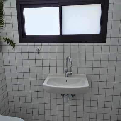 כיור לבן עם ברז כסוף על קיר מרוצף