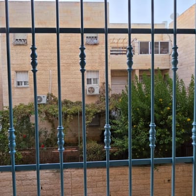 סורגים ישרים מברזל צבועים בתכלת בחלון דירה