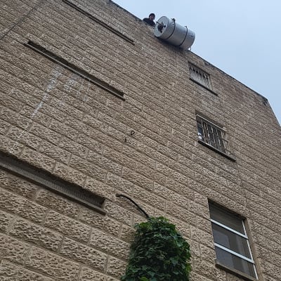 דוד שמש על גג בניין עם אדם לידו