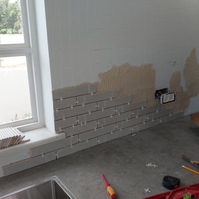 התקנת אריחים על קיר עם חוצצים וכלי עבודה