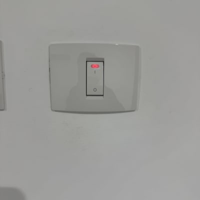 מתג חשמלי עם אור אדום על קיר לבן