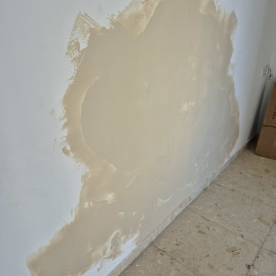 קיר עם תיקון טיח חלקי על רצפת אריחים