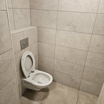 אסלה תלויה על קיר אריחים בחדר שירותים