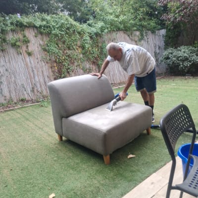 אדם מנקה ספה בחצר עם מכשיר ניקוי