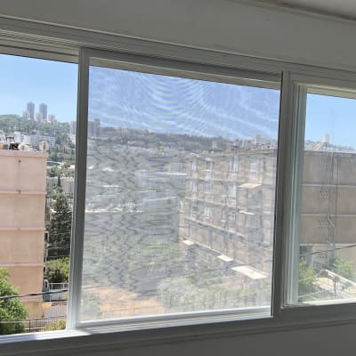 חלון אלומיניום עם מסגרת לבנה ונוף עירוני