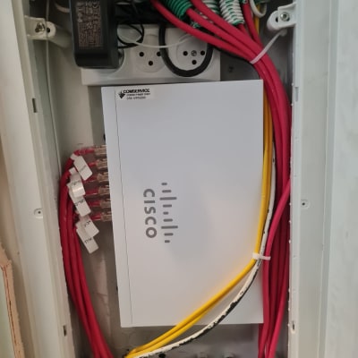 ארון תקשורת עם כבלים צבעוניים ומכשיר סיסקו