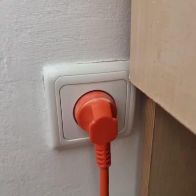תקע כתום בשקע חשמלי על קיר לבן