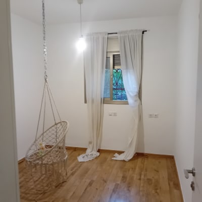 חדר פנימי צבוע בלבן מבריק עם רצפת פרקט וערסל תלוי