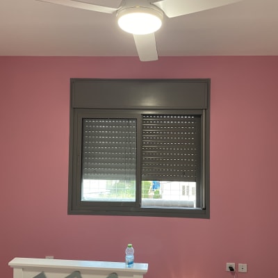 קיר צבוע בצבע ורוד עם חלון ומאוורר תקרה