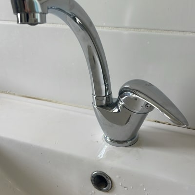 ברז כרום מותקן על כיור לבן עם חור ניקוז