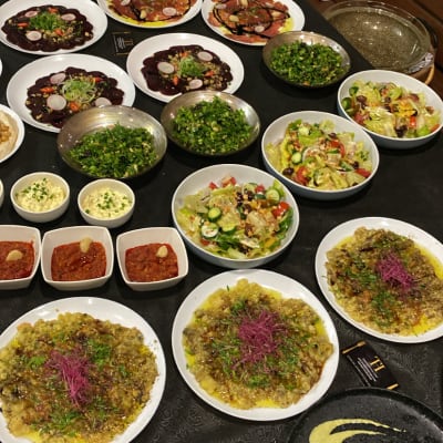 מגוון מנות שף על שולחן, כולל סלטים ומנות ראשונות.