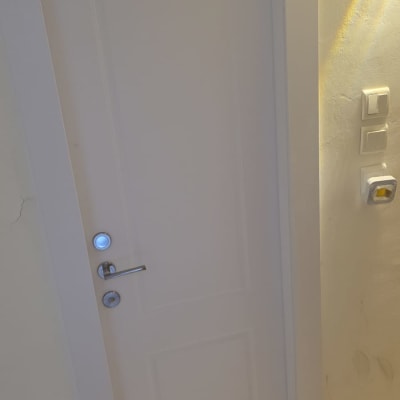 דלת לבנה עם ידית מתכת על קיר בהיר