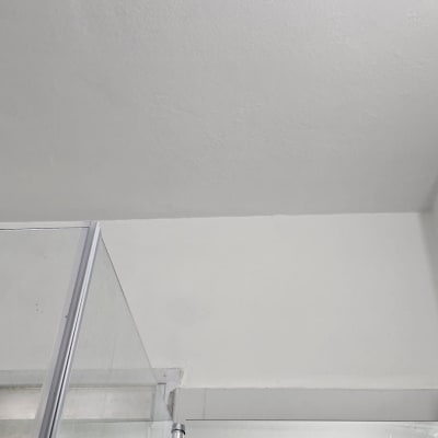 תקרה צבועה בלבן עם קיר זכוכית במקלחת