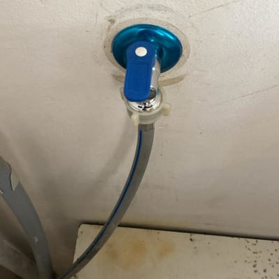 ברז כחול מחובר לצינור מים בקיר לבן